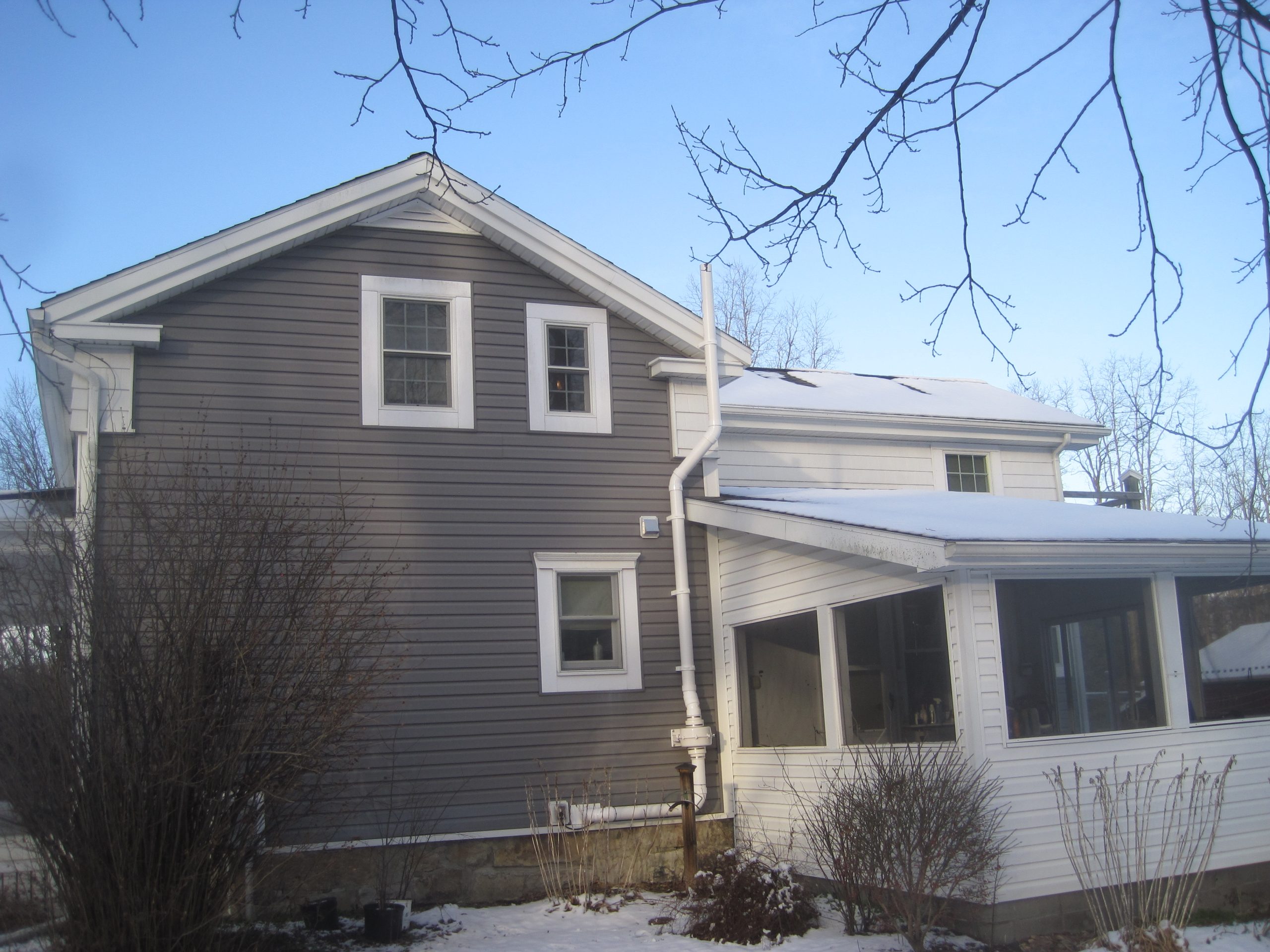 An image of a grey and white house from the exterior showing multiple windows and a radon exhaust system.